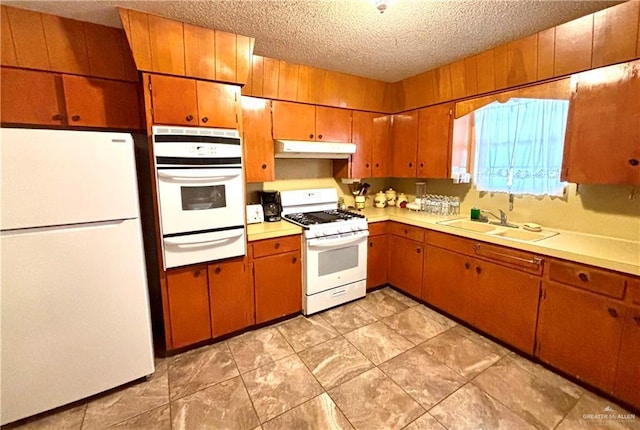 kitchen featuring light countertops, a sink, a textured ceiling, white appliances, and under cabinet range hood