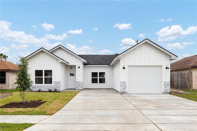 3513 E Adams Ave, Alton, TX 78573 - view of front of house featuring board and batten siding, an attached garage, driveway, and stone siding