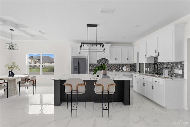 900 E 38th St, San Juan, TX 78589 - kitchen featuring a sink, decorative backsplash, a kitchen island, stainless steel refrigerator with ice dispenser, and visible vents