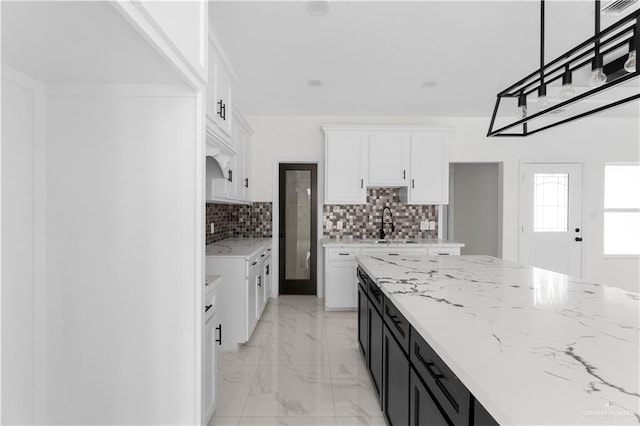 900 E 38th St, San Juan, TX 78589 - kitchen with marble finish floor, light stone counters, white cabinetry, tasteful backsplash, and dark cabinetry