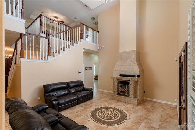 living room with tile patterned floors, ceiling fan, a fireplace, and a high ceiling