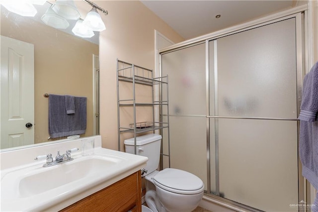 bathroom with a shower with door, vanity, and toilet