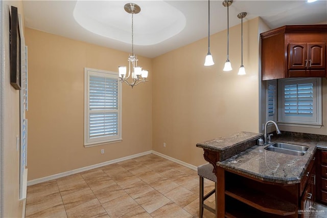 kitchen featuring a raised ceiling, sink, decorative light fixtures, and a notable chandelier