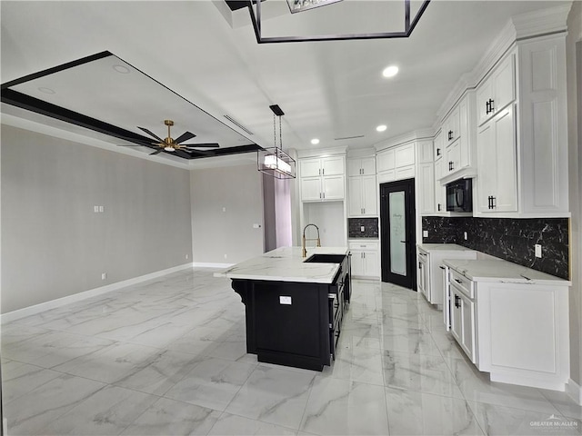 kitchen with tasteful backsplash, white cabinets, marble finish floor, black microwave, and a sink