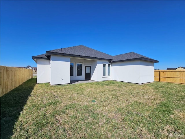 back of property with a lawn, a fenced backyard, and stucco siding