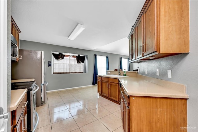 kitchen with light tile patterned floors, sink, appliances with stainless steel finishes, and kitchen peninsula