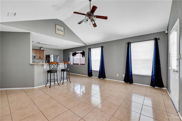 unfurnished living room with ceiling fan, light tile patterned floors, lofted ceiling, and a healthy amount of sunlight