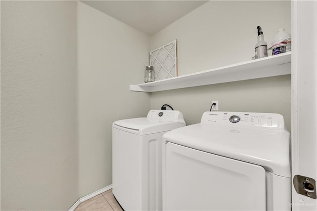 clothes washing area featuring light tile patterned flooring and washer and clothes dryer