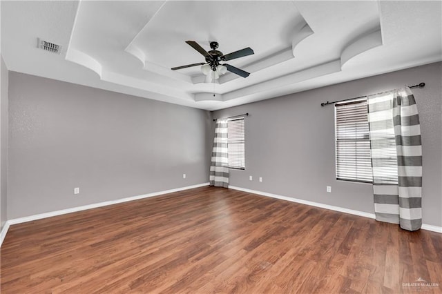 spare room featuring ceiling fan, a tray ceiling, and dark hardwood / wood-style flooring