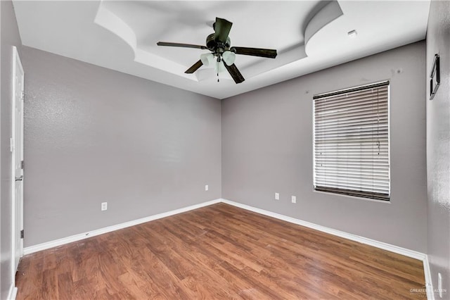 spare room featuring ceiling fan, hardwood / wood-style floors, and a raised ceiling