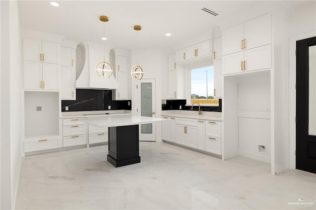 kitchen featuring tasteful backsplash, white cabinetry, a kitchen island, and hanging light fixtures