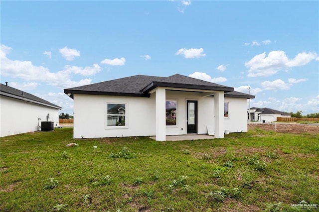 back of property with central air condition unit, a patio area, and a yard