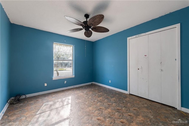 unfurnished bedroom featuring a ceiling fan, a closet, stone finish flooring, and baseboards