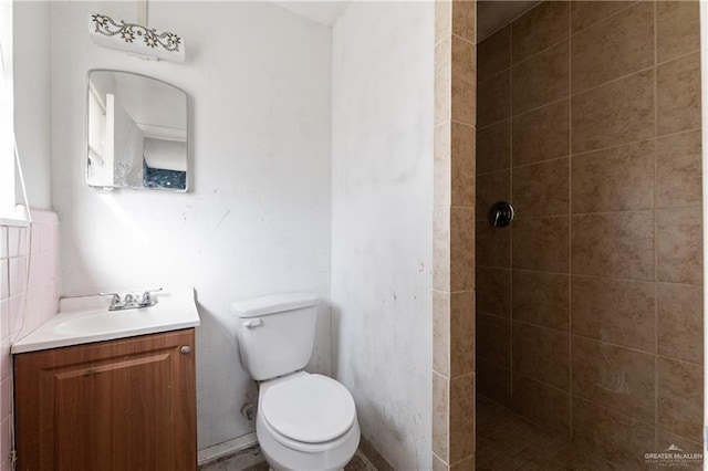 bathroom featuring toilet, tiled shower, and vanity