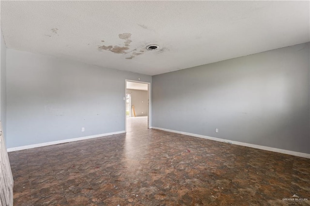 unfurnished room with a textured ceiling, visible vents, and baseboards