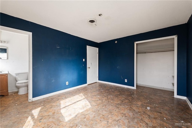 unfurnished bedroom featuring a closet, ensuite bath, visible vents, and baseboards