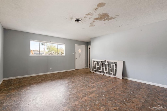 empty room with a textured ceiling, visible vents, and baseboards