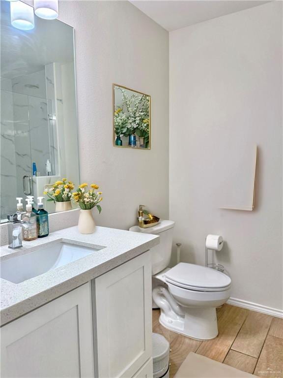 bathroom featuring toilet, an enclosed shower, and vanity