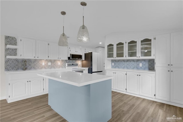 kitchen with hanging light fixtures, a kitchen island, white cabinets, white appliances, and backsplash