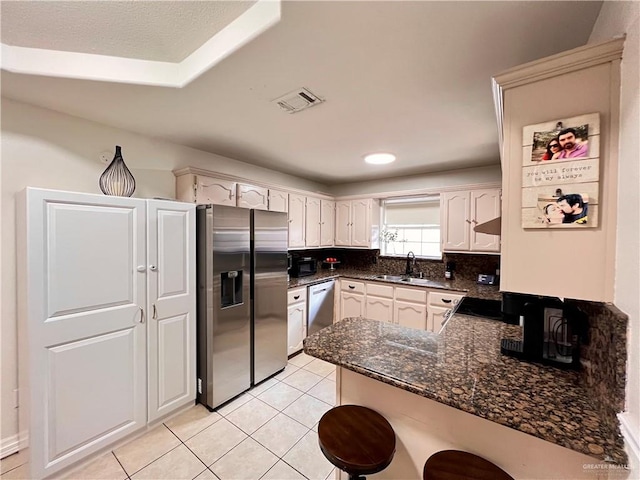 kitchen featuring backsplash, sink, appliances with stainless steel finishes, light tile patterned flooring, and kitchen peninsula