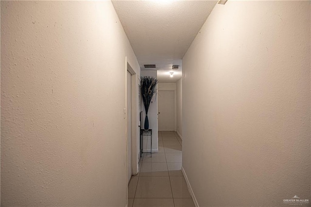 hallway with light tile patterned flooring and a textured ceiling