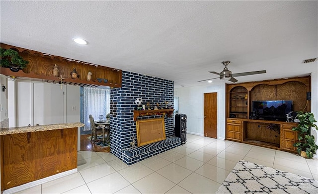 kitchen featuring ceiling fan, a fireplace, light tile patterned floors, and a textured ceiling