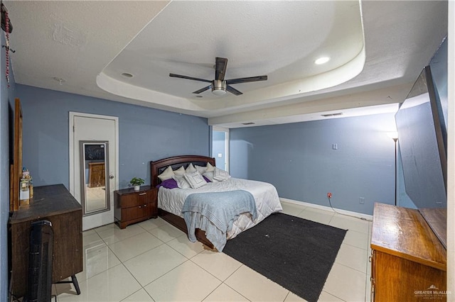 tiled bedroom with ceiling fan and a raised ceiling