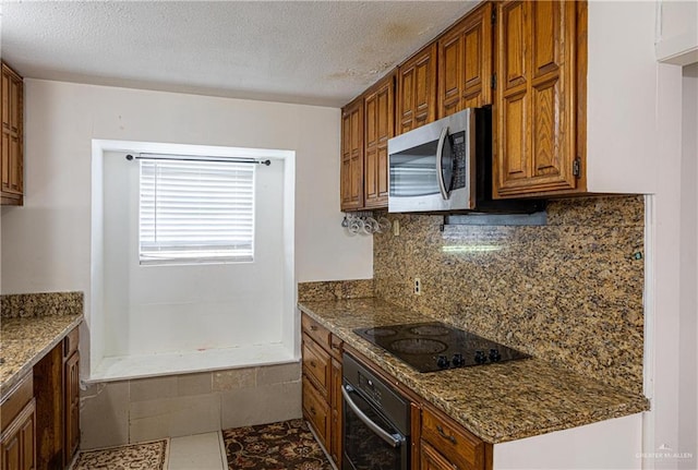 kitchen featuring black appliances, tile patterned flooring, dark stone countertops, and decorative backsplash