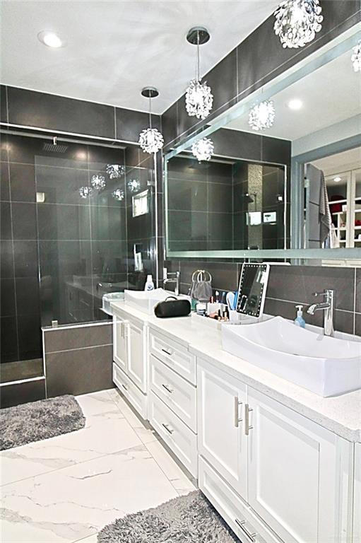 2209 David Ave, San Juan, TX 78589 - bathroom featuring tile walls, a sink, double vanity, and a tile shower