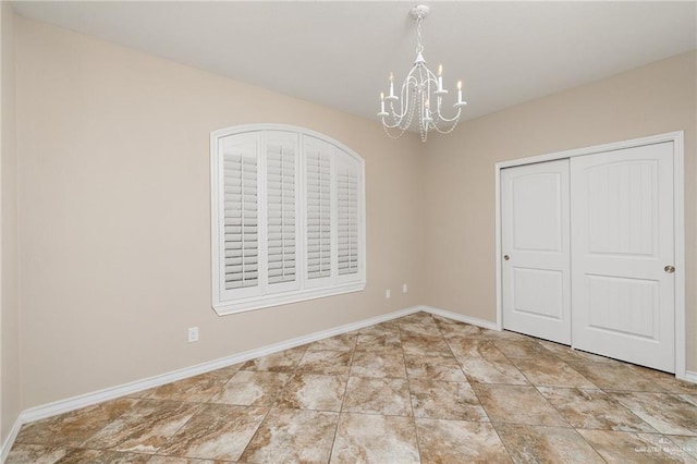 unfurnished room featuring a notable chandelier and baseboards