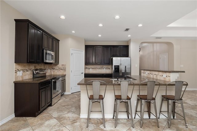 kitchen featuring a kitchen bar, visible vents, appliances with stainless steel finishes, and a sink