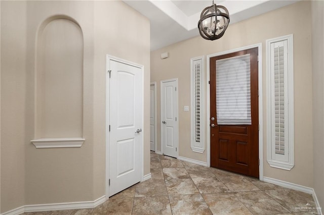 foyer with baseboards and an inviting chandelier