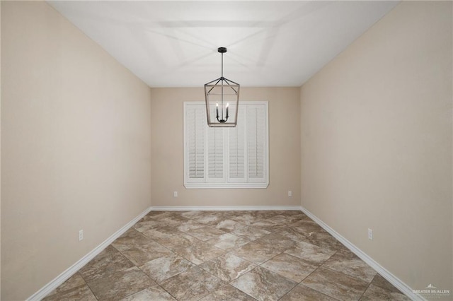 spare room with a chandelier and baseboards