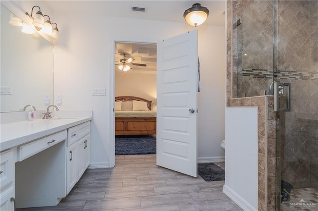 bathroom featuring vanity, toilet, ceiling fan, and a shower with shower door