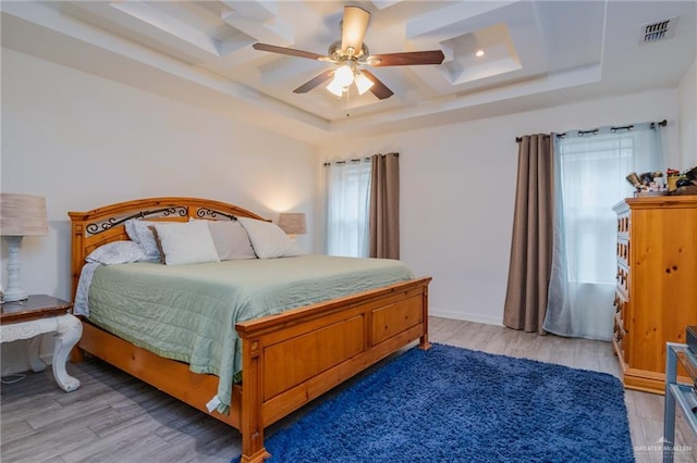 bedroom with hardwood / wood-style floors, a raised ceiling, and ceiling fan