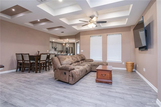 living room with coffered ceiling, beamed ceiling, ceiling fan, and light wood-type flooring