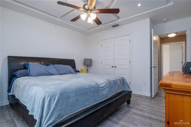 bedroom with a tray ceiling, a closet, and ceiling fan