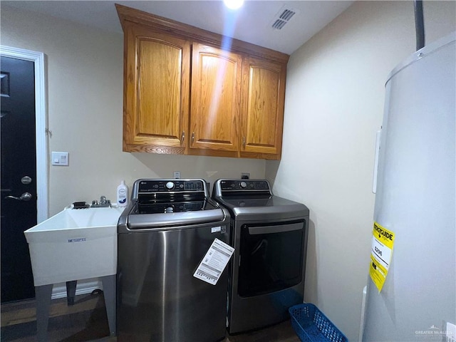 washroom with cabinets, independent washer and dryer, sink, and water heater