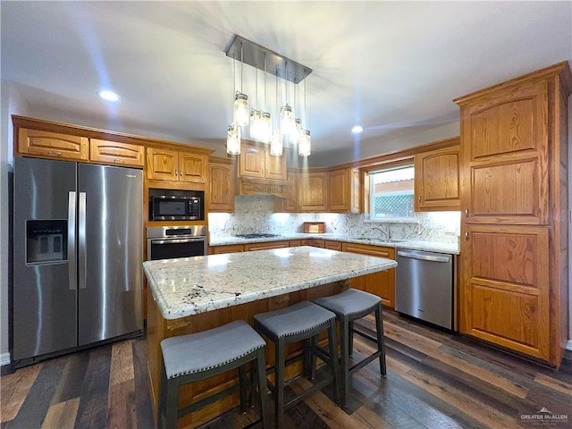 105 Lampshire Ln, Mission, TX 78572 - kitchen with appliances with stainless steel finishes, a kitchen island, backsplash, dark wood finished floors, and a kitchen bar