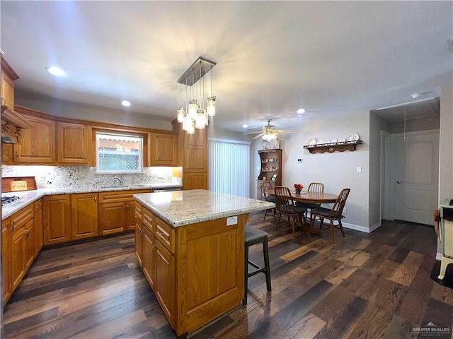 kitchen featuring pendant lighting, a center island, backsplash, sink, and dark hardwood / wood-style floors