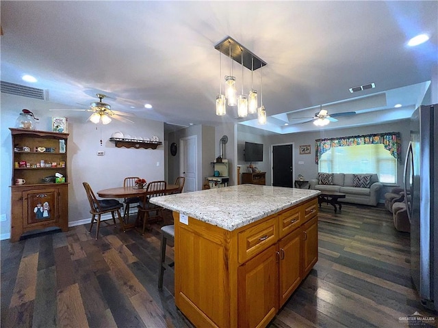 kitchen featuring a center island, dark hardwood / wood-style floors, stainless steel refrigerator, and hanging light fixtures