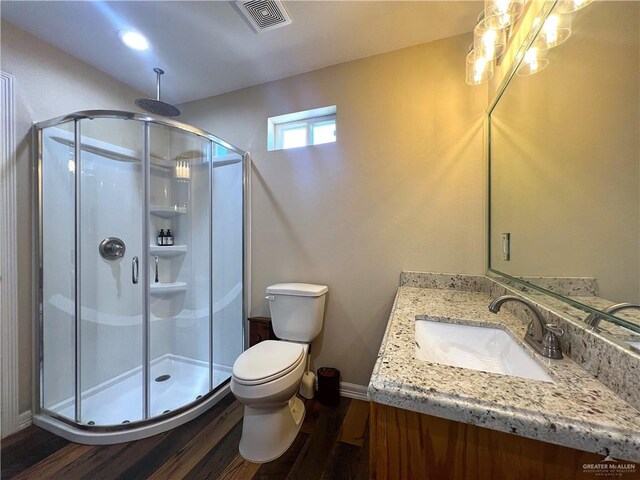 bathroom with hardwood / wood-style floors, vanity, toilet, and a shower with shower door