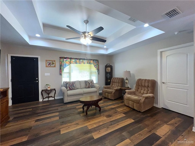 living room featuring a raised ceiling, ceiling fan, and dark hardwood / wood-style flooring