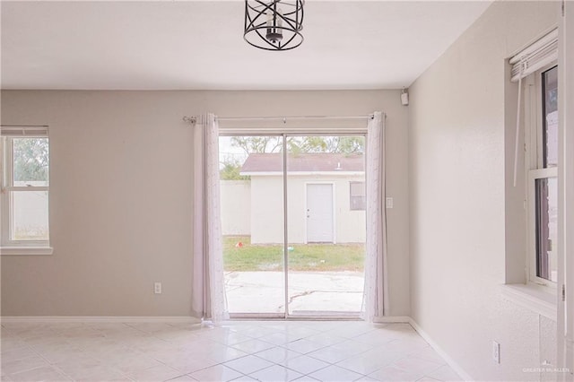 spare room with light tile patterned floors, a healthy amount of sunlight, and baseboards