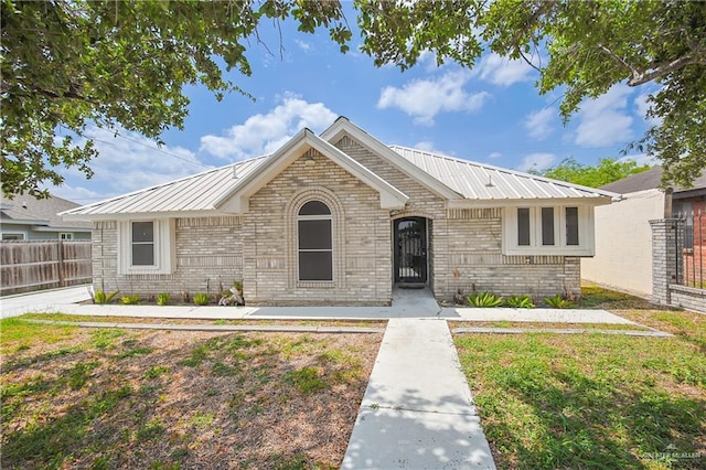ranch-style house with metal roof, fence, and brick siding