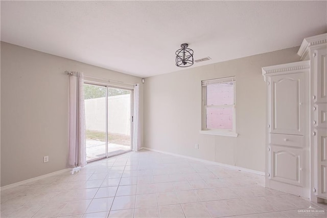 empty room with baseboards, visible vents, and light tile patterned floors