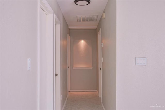 hall featuring baseboards and visible vents