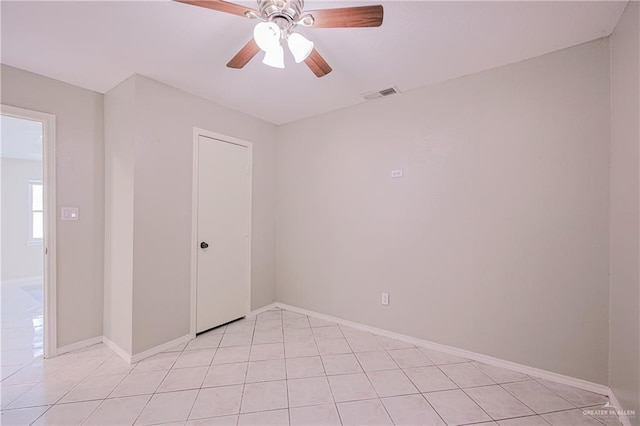 unfurnished room with light tile patterned floors, visible vents, a ceiling fan, and baseboards