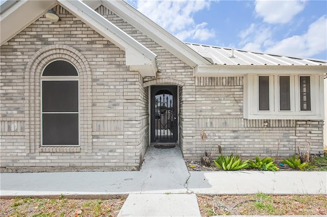 property entrance featuring metal roof and brick siding