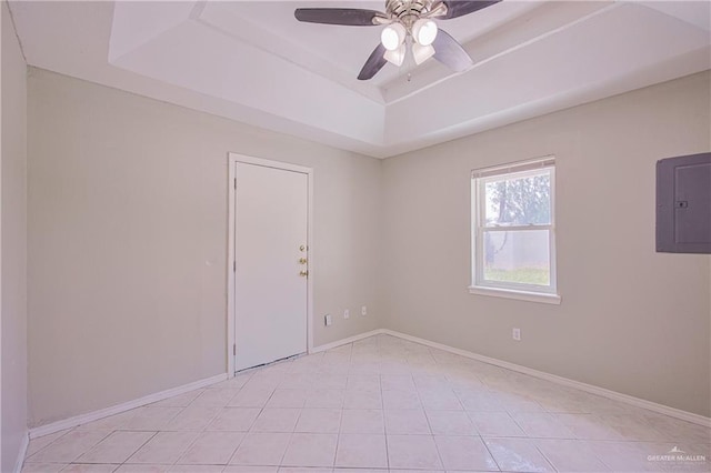 empty room with light tile patterned floors, a raised ceiling, electric panel, baseboards, and a ceiling fan